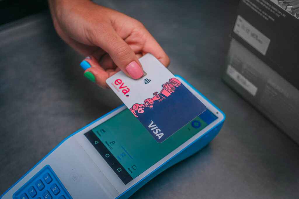 uma mão aproximando o cartão da Eva Benefícios numa máquina de cartão