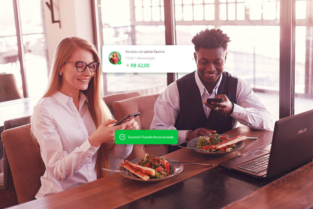 uma mulher e um homem sentados à mesa, cada um com um prato de comida. A mulher fez uma transferência pra ele e ele recebeu a notificação avisando da transferência