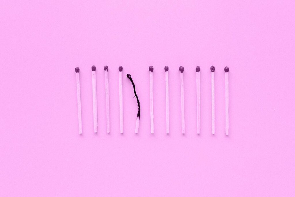 Palitos de fósforo alinhados e, no meio deles, um palito queimado.