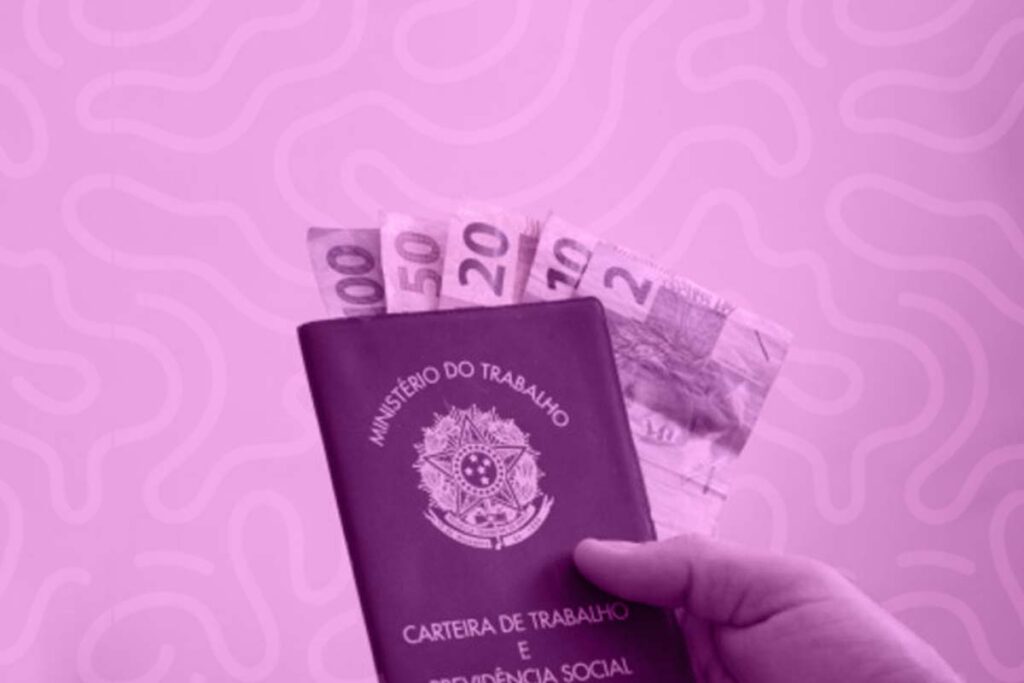 Na imagem há uma carteira de trabalho (CTPS), direito garantido pela CLT, com algumas notas de dinheiro dentro.