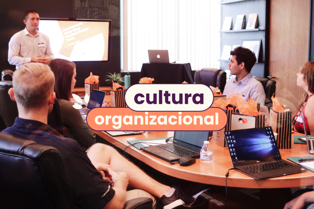 Pessoas em reunião em volta de uma mesa de madeira redonda. No título da imagem: "Cultura organizacional".