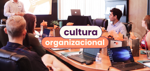 Pessoas em reunião em volta de uma mesa de madeira redonda. No título da imagem: "Cultura organizacional".