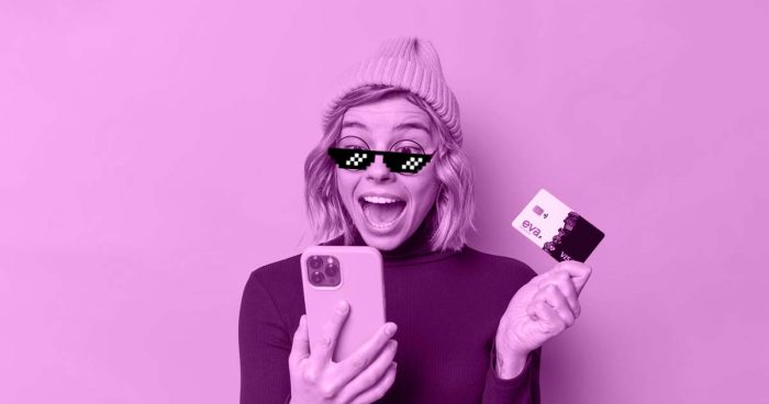 Mulher de touca e óculos escuros segurando o celular em uma mão e o Evacard em outra, com uma expressão de surpresa.