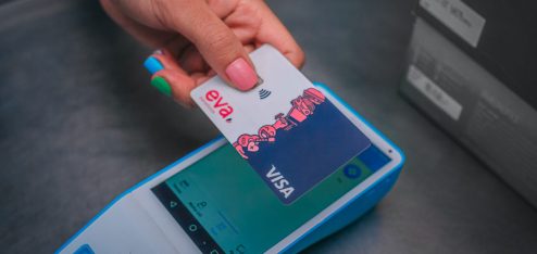 uma mão aproximando o cartão da Eva Benefícios numa máquina de cartão