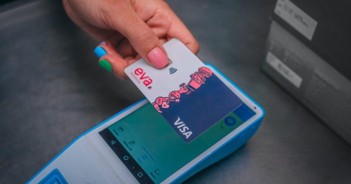 uma mão aproximando o cartão da Eva Benefícios numa máquina de cartão