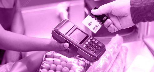 A imagem mostra as mãos de duas pessoas: uma caixa de supermercados segurando uma máquina de cartões e um cliente aproximando o cartão Eva da máquina.