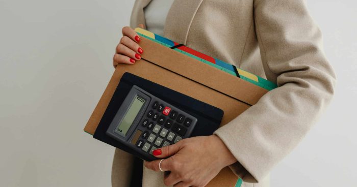 Mulher segurando uma calculadora e pastas organizadas, representando a importância da organização no trabalho e o uso de ferramentas adequadas para produtividade.